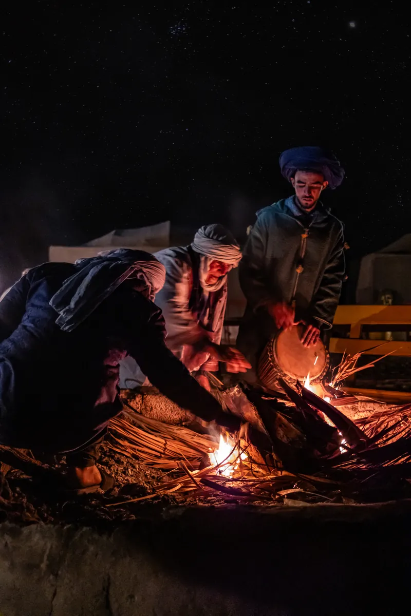 Uomini che si scaldano attorno a un fuoco di notte